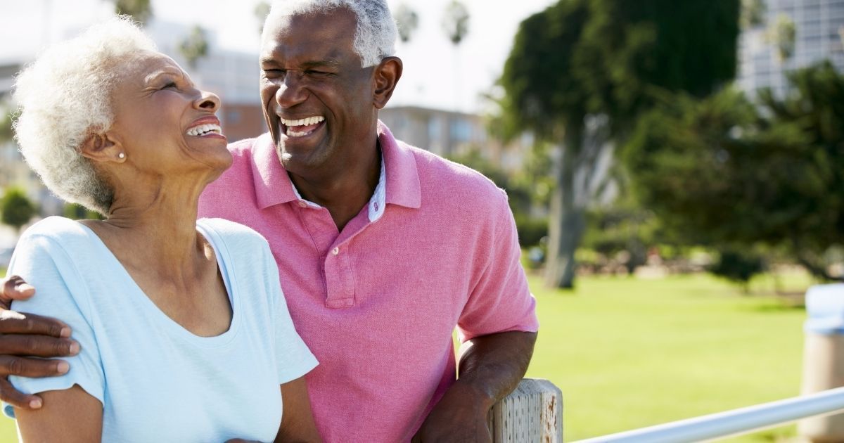 A man and woman laughing together outside.