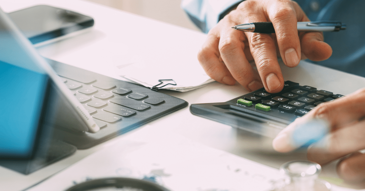 A person using a calculator on top of a desk.