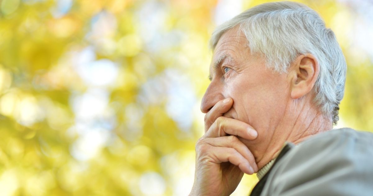 A man with his hand on his face looking up.